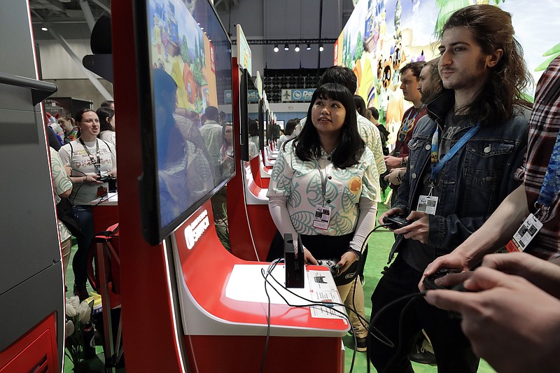 FILE - Visitors to the Pax East conference play the new Nintendo Switch video game Animal Crossing, Thursday, Feb. 27, 2020, in Boston. Thousands of gaming enthusiasts attended the Pax East conference that opened in Boston, Thursday. (AP Photo/Steven Senne)