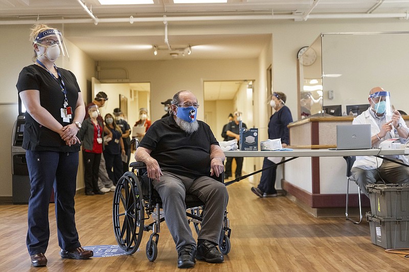 Photo by Hoang 'Leon' Nguyen / The Republican via The Associated Press, pool / U.S. Air Force Veteran Robert Aucoin, 78, arrives at the main lobby inside Soldiers' Home in Holyoke, Massachusetts for his COVID-19 vaccine dose as facility staffobserve on, Dec. 29, 2020.