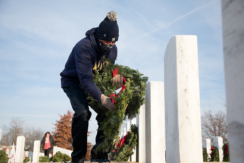 Staff photo by Troy Stolt / Mickey McCamish lays Christmas Wreaths at a grave as a part of "Wreaths Across America", an initiative to honor deceased veterans by laying Christmas wreaths at their graves at the National Cemetery on Saturday, Dec. 19, 2020, in Chattanooga, Tenn.