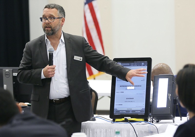 FILE - In this Thursday, Aug. 30, 2018 file photo, Eric Coomer from Dominion Voting demonstrates his company's touch screen tablet that includes a paper audit trail at the second meeting of Secretary of State Brian Kemp's Secure, Accessible & Fair Elections Commission in Grovetown, Ga. Eric Coomer, driven into hiding by death threats has filed a defamation lawsuit against President Donald Trump's campaign, two of its lawyers and some conservative media figures and outlets, Tuesday, Dec. 22, 2020. (Bob Andres/Atlanta Journal-Constitution via AP, File)