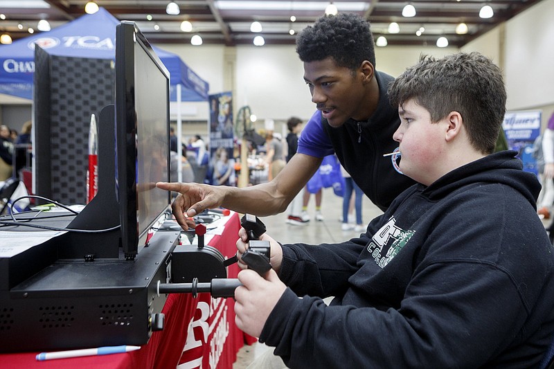 Staff photo by C.B. Schmelter / Loftis Middle School eighth grader Mason Booker, right, gets help from Brainerd High School student ambassador Justin Lewis while using the flight simulator at the Institue of Aviation at Brainerd High School booth during the Get (Future) Ready school choice fair at the Chattanooga Convention Center on Wednesday, Jan. 15, 2020 in Chattanooga, Tenn.