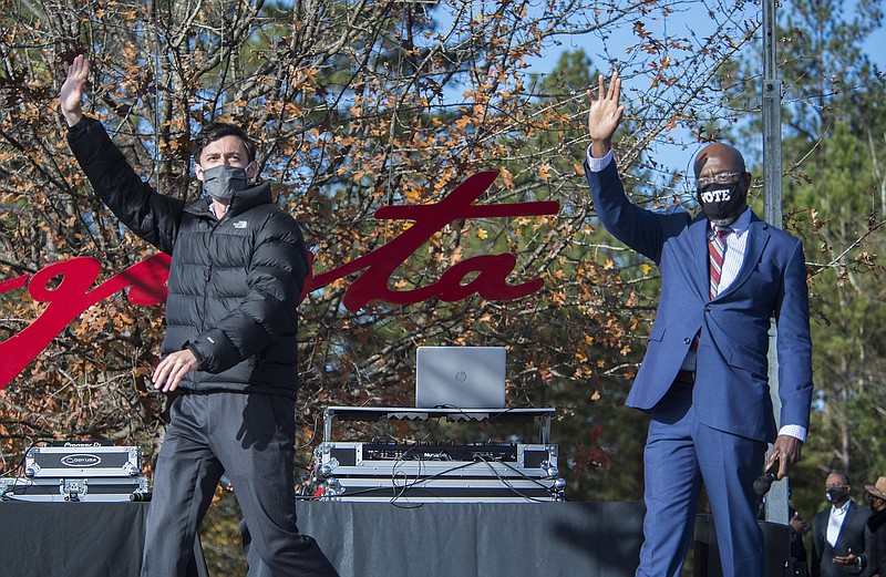 Jon Ossoff, left, and Raphael Warnock wave to the crowd during a campaign rally in Augusta, Ga., Monday, Jan. 4, 2021. Democrats Ossoff and Warnock are challenging incumbent Republican Senators David Perdue and Kelly Loeffler in a runoff election on Jan. 5. (Michael Holahan/The Augusta Chronicle via AP)