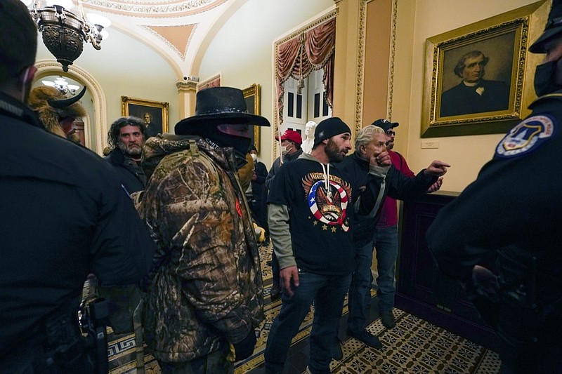 Protesters walk as U.S. Capitol Police officers watch in a hallway near the Senate chamber at the Capitol in Washington, Wednesday, Jan. 6, 2021, near the Ohio Clock. (AP Photo/Manuel Balce Ceneta)