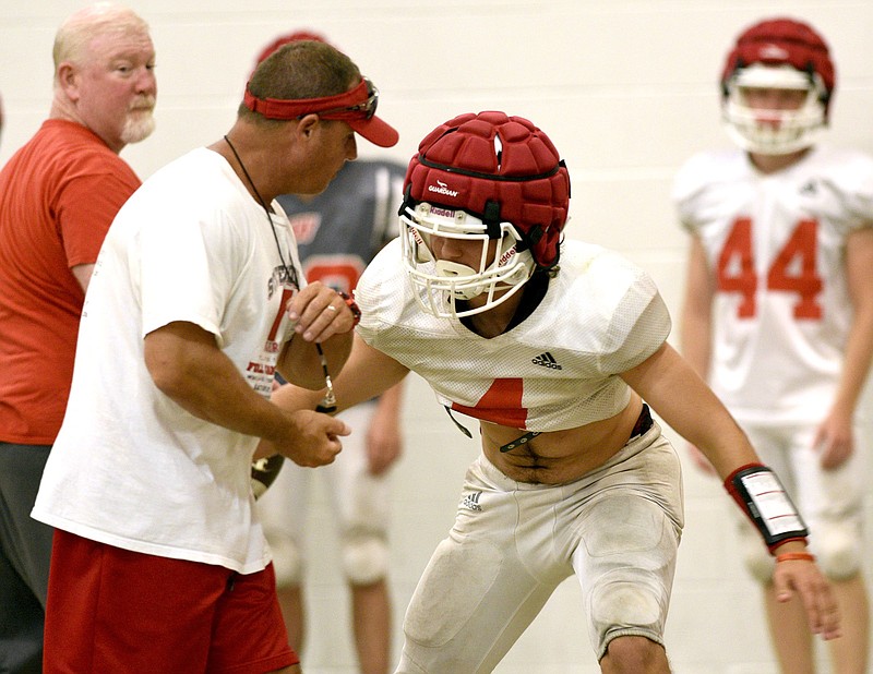 Staff Photo by Robin Rudd/  Whitwell's Jacob Winchester (4) runs through a drill with assistant coach Rocky Stephenson while assistant coach Jacky Blosser looks on.  Weather forced the Whitwell Tigers inside for practice on August 7, 2019.  The Tigers used the Whitwell Elementary School gym.  
