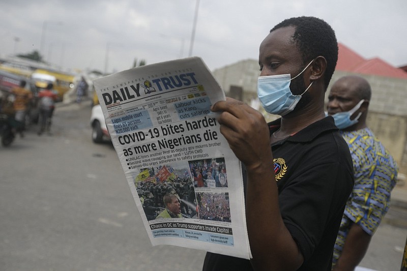 A man reads a newspaper reacting to the news of the assault on U.S Congress, on a street in Lagos, Nigeria, Thursday Jan. 7, 2021. News reports show police with gun drawn as protesters try to break into the House Chamber at the U.S. Capitol on Wednesday, Jan. 6, in Washington, USA.(AP Photo/ Sunday Alamba)
