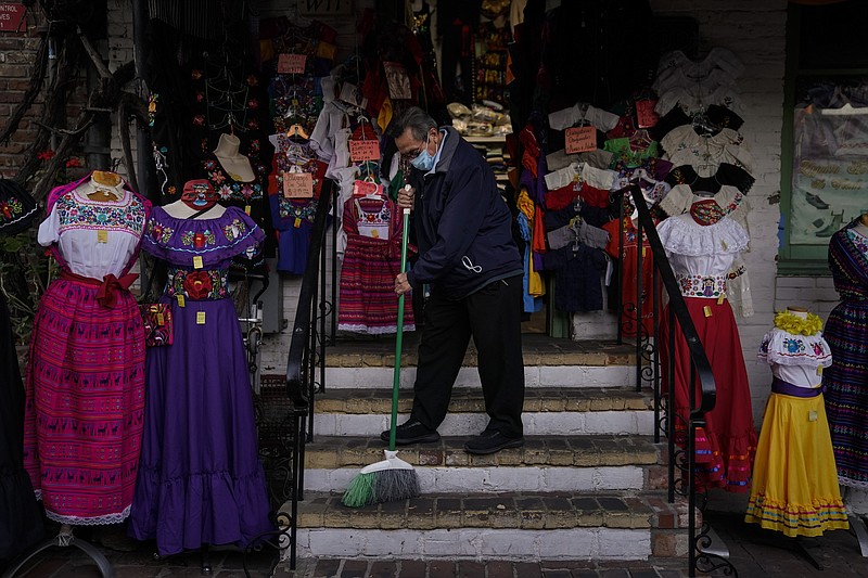 Victor Flores, 66, a third-generation owner of a gift shop, sweeps the steps of his store on Olvera Street in downtown Los Angeles, Wednesday, Dec. 16, 2020. Millions of business owners are about to get additional help as they weather the coronavirus outbreak. The Small Business Administration and the Treasury Department are reviving the Paycheck Protection Program five months after its first two rounds of funding ended. (AP Photo/Jae C. Hong, file)