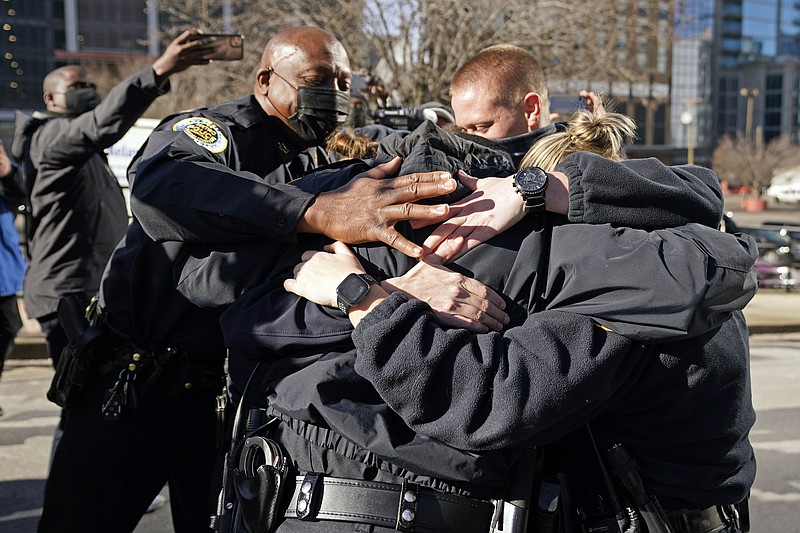 Nashville Police Chief John Drake, left, joins a group of police officers as they embrace after speaking at a news conference Sunday, Dec. 27, 2020, in Nashville, Tenn. The officers are part of a group of officers credited with evacuating people before an explosion took place in downtown Nashville early Christmas morning. (AP Photo/Mark Humphrey)