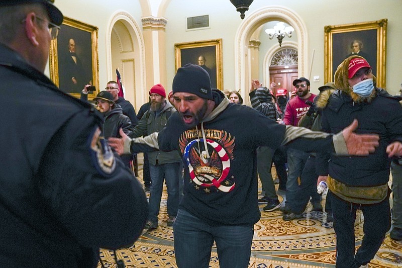 FILE - In this Jan. 6, 2021, file photo, Trump supporters gesture to U.S. Capitol Police in the hallway outside of the Senate chamber at the Capitol in Washington. Doug Jensen, an Iowa man at center, was jailed early Saturday, Jan. 9, 2021 on federal charges, including trespassing and disorderly conduct counts, for his alleged role in the Capitol riot. Jensen, 41, of Des Moines, was being held without bond at the Polk County Jail and county sheriff's Sgt. Ryan Evans said he didn't know if Jensen had an attorney. (AP Photo/Manuel Balce Ceneta, File)