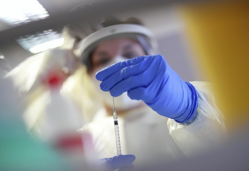 A member of a mobile vaccination team prepares a Covid-19 vaccination with Pfizer/Biontech vaccine for nursing home residents at a nursing home in Oberammergau, Germany, Monday, Jan. 11, 2021. (Angelika Warmuth/dpa via AP)