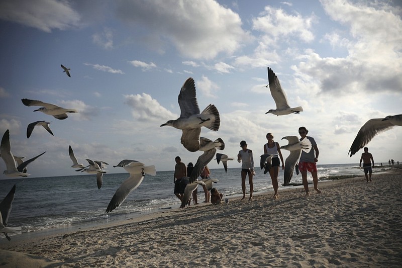 Tourists stroll on the shore of Xcalacoco beach in Playa del Carmen, Quintana Roo state, Mexico, Wednesday, Jan. 6, 202, amid the new coronavirus pandemic. Quintana Roo, the country's tourism crown jewel, home to Cancun, the Riviera Maya and Tulum, received more than 900,000 tourists spanning the end of 2020 and the start of 2021. (AP Photo/Emilio Espejel)