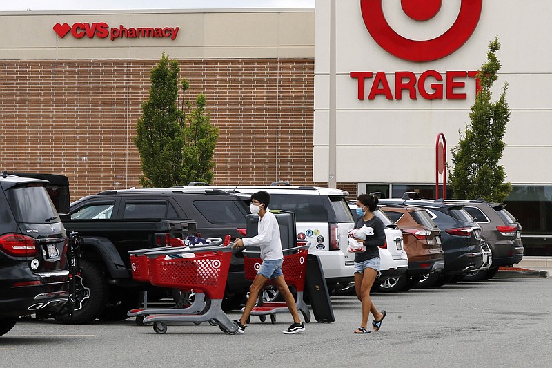 FILE - In this Aug. 4, 2020 file photo, shoppers take purchases to their vehicle in the parking lot of a Target store in Marlborough, Mass. Target's strong sales streak extended through the holiday season, as shoppers snapped up everything from clothing to home goods during the pandemic. The Minneapolis company reported Wednesday, Jan. 13, 2021, that its online sales surged 102% for the November and December period. (AP Photo/Bill Sikes)