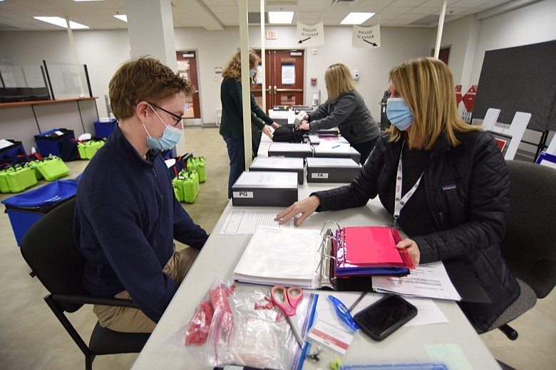 Staff Photo by Matt Hamilton / Landon Smith, left, talks with Whitfield County Registrar Mary Hammontree, left, as he picks up polling place materials at the Whitfield County Elections Office at the Whitfield County Courthouse in Dalton, Ga. on Monday, Jan. 4, 2021. As Andrea Springfield, back right, with the Whitfield County Elections Office, gives other polling place materials to Ella Talley. Talley and Smith are in charge of the polling place in Varnell, Ga.