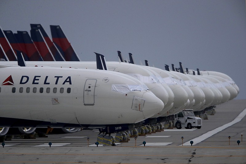 FILE - In this May 14, 2020 file photo, several dozen mothballed Delta Air Lines jets are parked on a closed runway at Kansas City International Airport in Kansas City, Mo. Delta Air Lines is reporting a $755 million loss for the fourth quarter, which brings its loss for all of 2020 to more than $12 billion. And Delta gave a cautious outlook Thursday, Jan. 14, 2021, for the first quarter of 2021, saying it expects to lose $10 million to $15 million a day in the next three months. (AP Photo/Charlie Riedel, File)