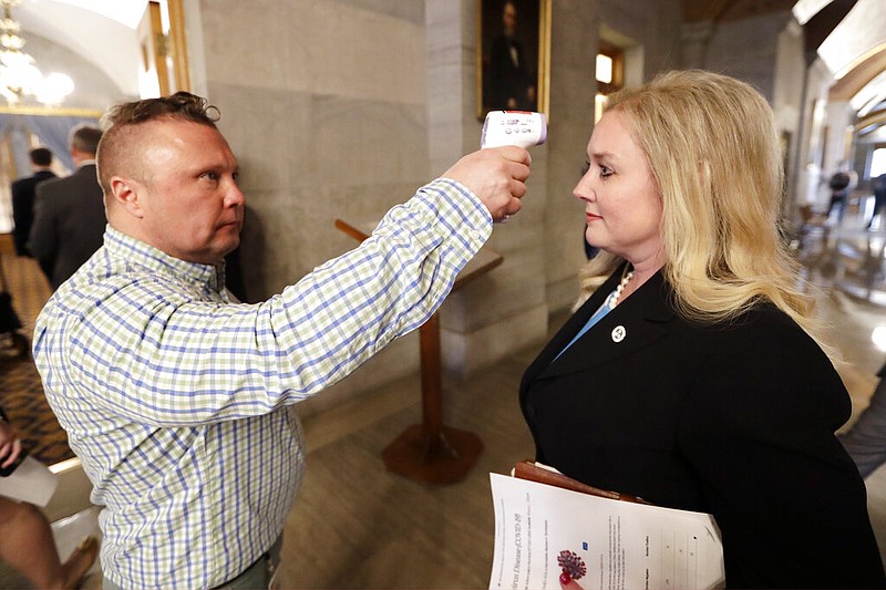 Tennessee Health Commissioner Lisa Piercey has her temperature taken by Scott Wyatt, left, of the Tennessee Department of Health as Piercey arrives for a news conference concerning the state's response to the coronavirus Monday, March 16, 2020, in Nashville, Tenn. (AP Photo/Mark Humphrey)