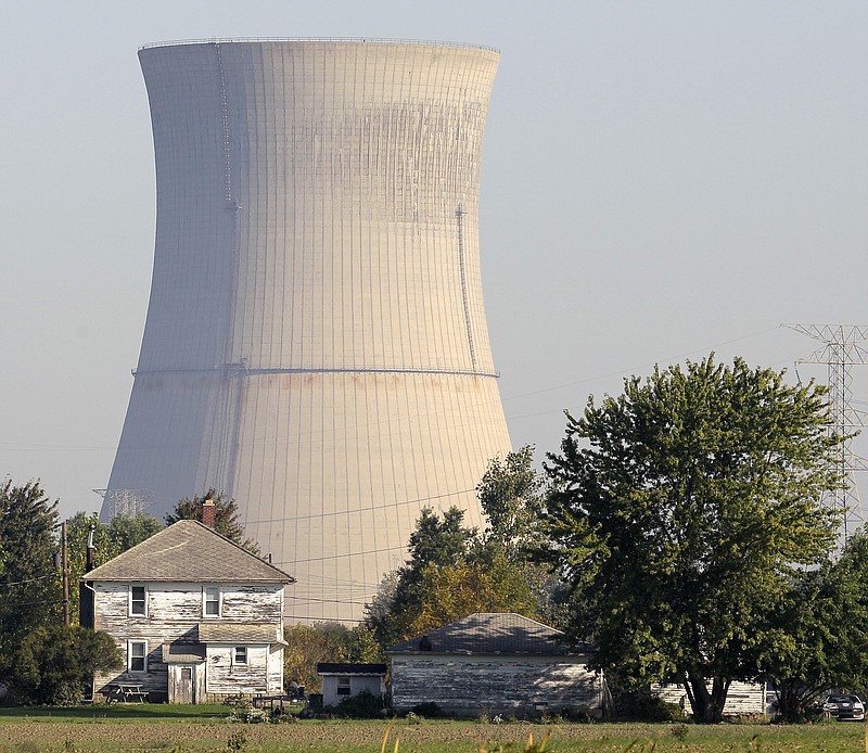 FILE-In this Oct. 5, 2011 file photo, the cooling tower of the Davis-Besse Nuclear Power Station looms over an adjacent farm in Oak Harbor, Ohio. Across the nation, a handful of nuclear plants unable to compete with natural gas and renewable energy have shut down within the last two years, taking away steady and lucrative sources of tax money for schools, roads and libraries. The uncertainty surrounding the future of both Ohio plants, Davis-Besse near Toledo and Perry near Cleveland, has created plenty of nervousness in their hometowns that have found themselves caught in the middle of the scandal-tainted bailout. (AP Photo/Amy Sancetta, File)