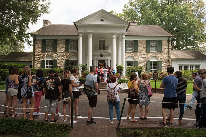 In an Aug. 15, 2017 file photo, fans wait in line outside Graceland, Elvis Presley's Memphis home, in Memphis, Tenn. Elvis Presley's Graceland says it will reopen Thursday, May 21, 2020 after it shut down tours and exhibits due to the new coronavirus outbreak. The tourist attraction in Memphis, Tennessee, said Sunday that it has adjusted its tours, and restaurant and retail operations, since it closed in March. (AP Photo/Brandon Dill, File)