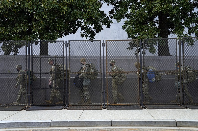 Troops walk behind security fencing on Saturday, Jan. 16, 2021, in Washington as security is increased ahead of the inauguration of President-elect Joe Biden and Vice President-elect Kamala Harris. (AP Photo/John Minchillo)


