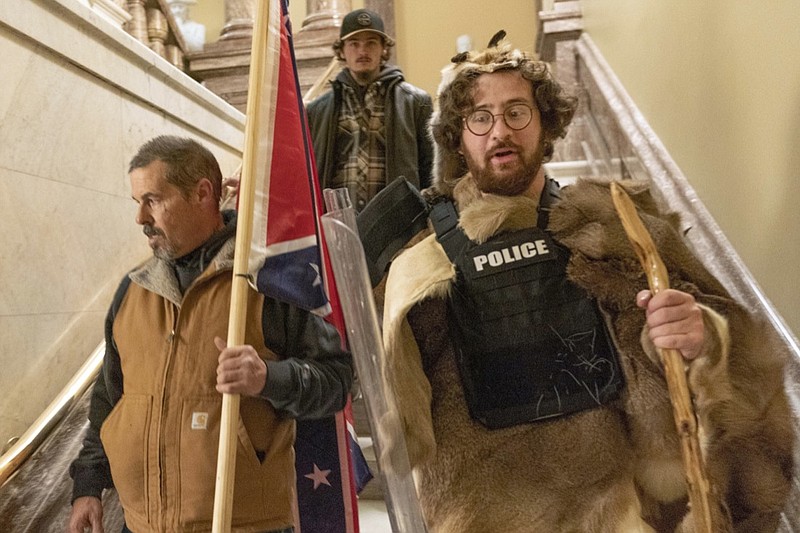 FILE - In this Jan. 6, 2021 file photo, insurrectionists loyal to President Donald Trump, including Aaron Mostofsky, right, and Kevin Seefried, left, walk down the stairs outside the Senate Chamber in the U.S. Capitol, in Washington. More than 125 people have been arrested so far on charges related to the violent insurrection at the U.S. Capitol, where a Capitol police officer and four others were killed. (AP Photo/Manuel Balce Ceneta, File)