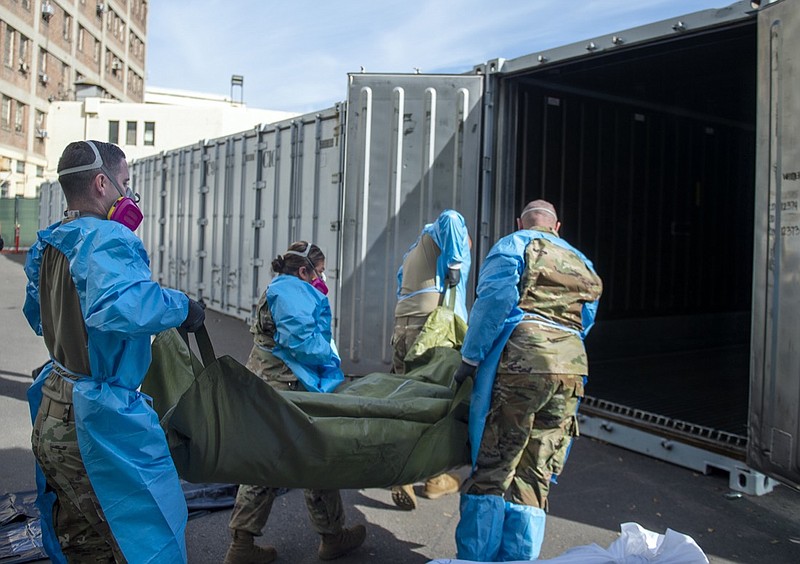 FILE - In this Jan. 12, 2021 photo provided by the Los Angeles County Department of Medical Examiner-Coroner, National Guard members assisting with processing COVID-19 deaths, placing them into temporary storage at the medical examiner-coroner's office in Los Angeles. The seven-day rolling average of daily deaths is rising in 30 states and the District of Columbia, and on Monday, Jan 18, 2021, the U.S. was approaching 398,000, according to data collected by Johns Hopkins University, by far the highest of any country in the world. (Los Angeles County Department of Medical Examiner-Coroner via AP, File)