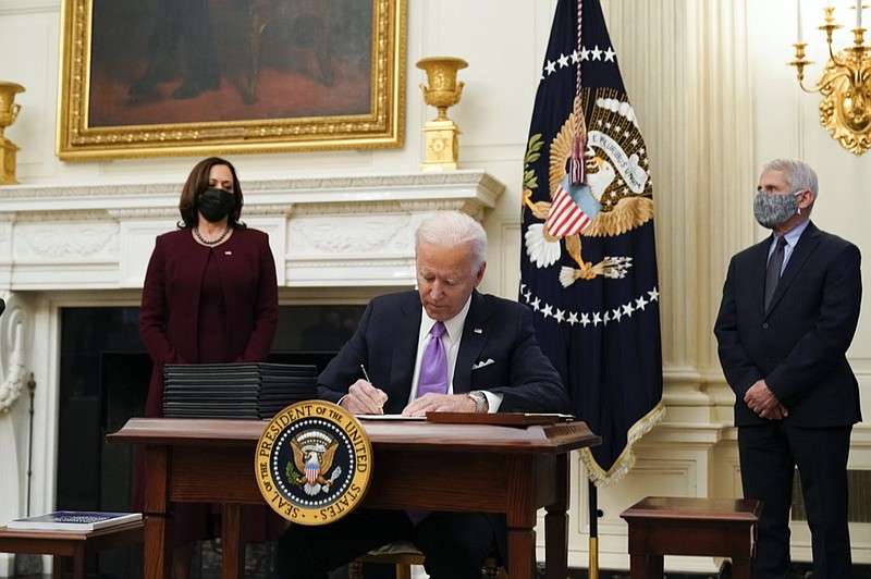 President Joe Biden signs executive orders after speaking about the coronavirus, accompanied by Vice President Kamala Harris, left, and Dr. Anthony Fauci, director of the National Institute of Allergy and Infectious Diseases, right, in the State Dinning Room of the White House, Thursday, Jan. 21, 2021, in Washington. (AP Photo/Alex Brandon)


