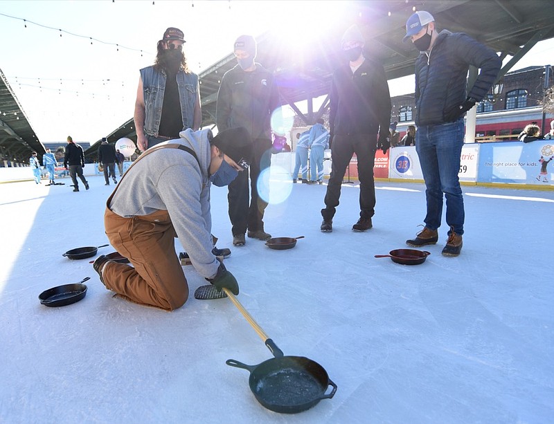 Staff Photo by Matt Hamilton / Ben Mattson uses a broom handle to measure the distance of the skillets to determine scoring after a round at the Chattanooga Choo Choo on Saturday, Jan. 23, 2021.
