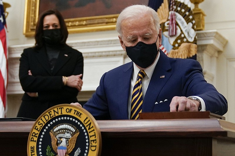 President Joe Biden signs executive orders on the economy in the State Dining Room of the White House, Friday, Jan. 22, 2021, in Washington. Vice President Kamala Harris looks on at left. (AP Photo/Evan Vucci)


