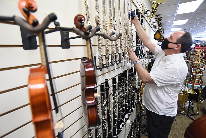 Staff photo by Matt Hamilton / Owner Darren Patrick straightens a display of flutes at Mountain Music in Hixson. The store allows customers to rent to own instruments from violins to electric guitars.