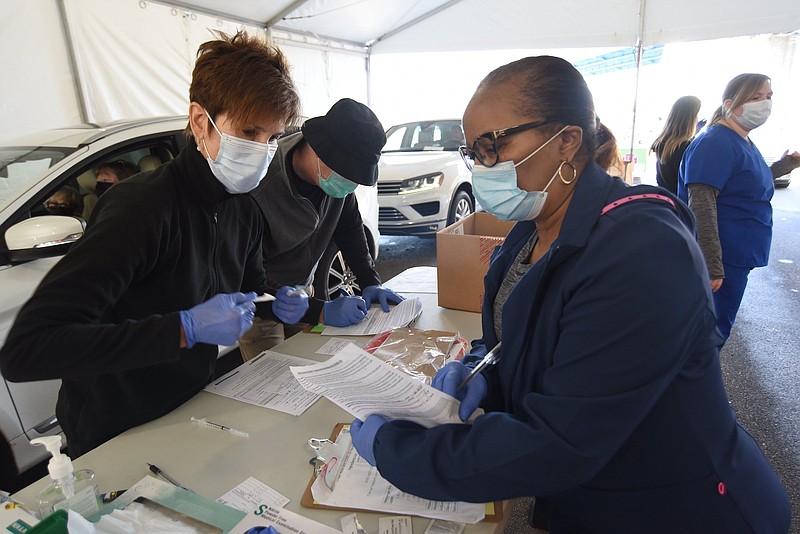 Staff Photo by Matt Hamilton / Nurses Mary Laughlin, left, and Darlena Toney, right, and Dr. Peter Rawlings, middle, fill out paperwork and administer doses of COVID-19 vaccine at the vaccination site at the Tennessee Riverpark on Tuesday, Jan. 26, 2021. 