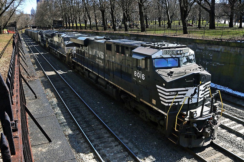 FILE- In this March 26, 2018, file photo, a Norfolk Southern freight train rolls through downtown Pittsburgh. Norfolk Southern's fourth-quarter profit improved slightly even though it hauled 1% less freight because the railroad controlled expenses tightly as the economy continued to slowly recover from last year's widespread shutdowns during the coronavirus pandemic. (AP Photo/Gene J. Puskar, File)