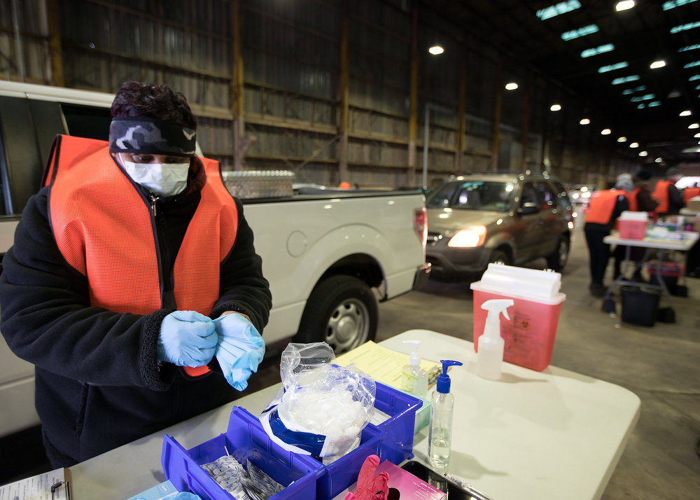 Staff photo by Troy Stolt / LPN Adrian Price changes gloves before administering a dose of the Moderna COVID-19 vaccine at the Hamilton County Health Department's new COVID Vaccination POD at the CARTA Bus Terminal on Thursday, Jan. 28, 2021 in Chattanooga, Tenn.
