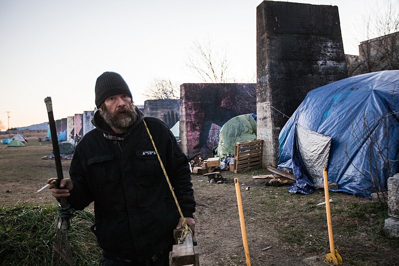 Staff photo by Troy Stolt / Jon Kavanaugh carries a wooden palate from a homeless encampment on East 11th Street while helping a friend set up an encampment of his own on Thursday, Jan. 28, 2021, in Chattanooga, Tenn.