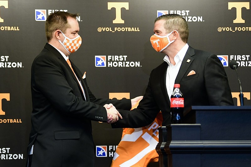 New Tennessee NCAA college football head coach Josh Heupel, left, shakes hands with University of Tennessee athletics director Danny White after being presented a jersey speaks during an introductory press conference at Neyland Stadium in Knoxville, Tenn., Wednesday, Jan. 27, 2021. (Caitie McLekin/Knoxville News Sentinel via AP, Pool)