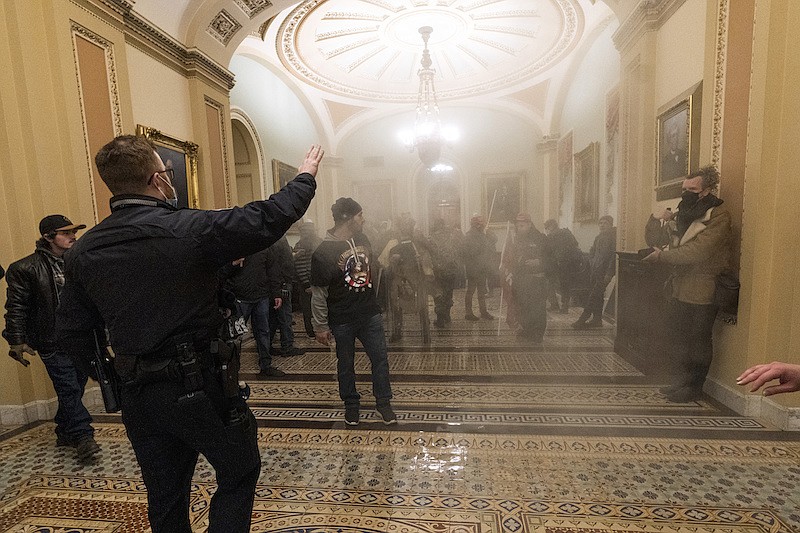In this Jan. 6, 2021, file photo, smoke fills the walkway outside the Senate Chamber as supporters of President Donald Trump are confronted by U.S. Capitol Police officers inside the Capitol in Washington. Federal prosecutors are linking a Nevada man and a Tennessee man arrested in Las Vegas on charges arising from U.S. Capitol rioting with an Idaho man arrested earlier this month in Boise. Nathan DeGrave and Ronald Sandlin remained in federal custody Friday, Jan. 29, 2021, pending an initial court appearance Monday before a U.S. magistrate judge in Las Vegas. (AP Photo/Manuel Balce Ceneta, File)