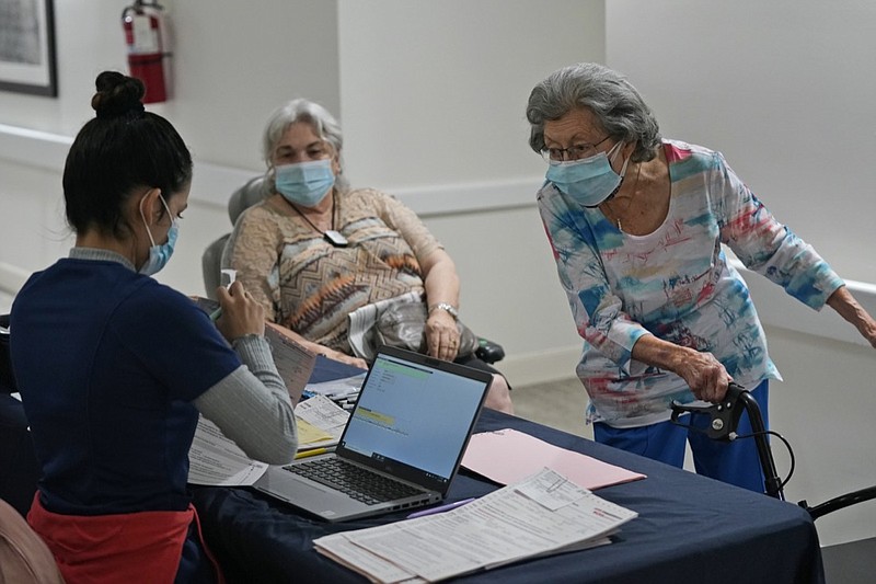 Mitzi Hansrote, right, 86, and Deanna Sutton, center, 83, check in before receiving the COVID-19 vaccine, Thursday, Jan. 21, 2021, at the Isles of Vero Beach assisted and independent senior living community in Vero Beach, Fla. Government officials placed long-term care residents and staff among their top vaccination priorities after they authorized the emergency use of shots from Pfizer and Moderna in late 2020. (AP Photo/Wilfredo Lee)