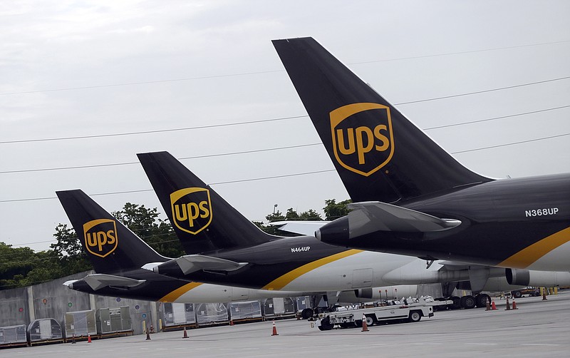 In this July 27, 2020 file photo, the tails of three UPS aircraft are shown parked at Miami International Airport in Miami. UPS, whose brown delivery trucks have become omnipresent on neighborhood streets during the pandemic, is reporting strong profits and revenue in its most recent quarter. (AP Photo/Wilfredo Lee, File)