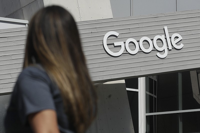 FILE - In this Sept. 24, 2019, file photo, a woman walks below a Google sign on the campus in Mountain View, Calif. In results announced Tuesday, Feb. 2, 2021, Google's digital advertising empire is regaining the momentum it lost during the pandemic's early stages. And its YouTube video service is maturing into a major marketing magnet and companies are anticipating more spending by cooped-up consumers when the economy reopens. (AP Photo/Jeff Chiu, File)