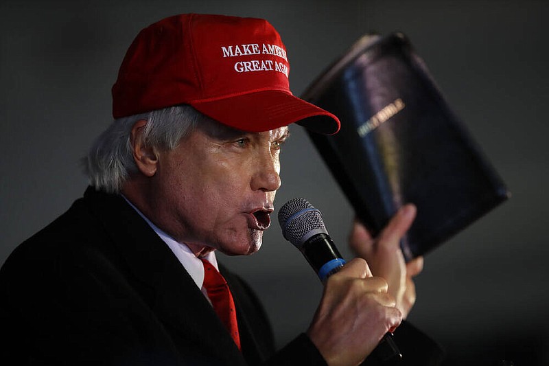 Attorney Lin Wood, member of President Donald Trump's legal team, holds a bible while speaking during a rally on Friday, Dec. 2, 2020, in Alpharetta, Ga. (AP Photo/Ben Margot)