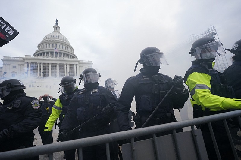 FILE - In this Jan. 6, 2021, file photo, police stand guard after holding off Trump supporters who tried to break through a police barrier at the Capitol in Washington. As federal officials grapple with how to confront the national security threat from domestic extremists after the deadly siege of the U.S. Capitol, civil rights groups and communities of color are watching warily for any moves to expand law enforcement power or authority. (AP Photo/Julio Cortez, File)