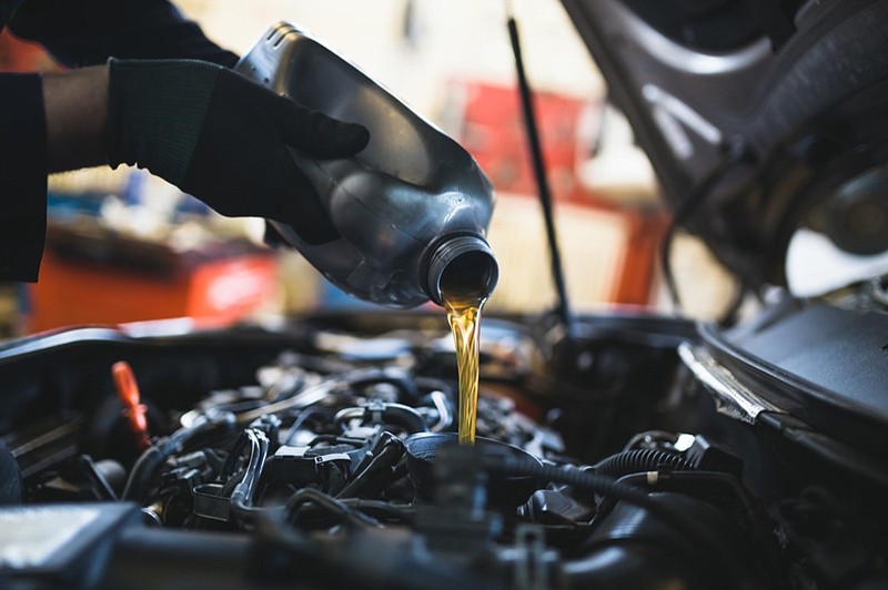 Close up hands of unrecognizable mechanic doing car service and maintenance car tile oil change tile / Getty Images
