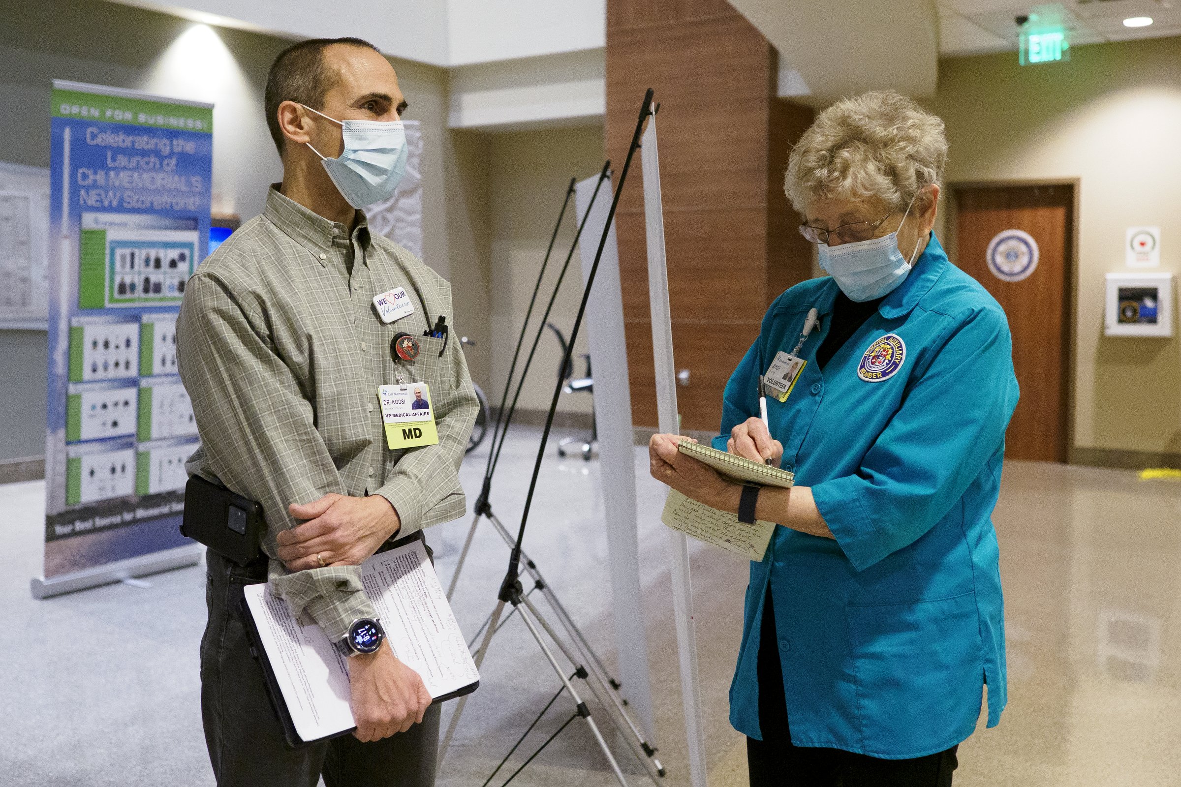 Staff photo by C.B. Schmelter / Volunteer Joyce Dick, right, takes notes as she talks with Vice President of Medical Affairs Dr. Matt Kodsi at CHI Memorial Hospital on Monday, Feb. 1, 2021 in Chattanooga, Tenn. The hospital welcomed back volunteers who have been fully vaccinated. Joyce Dick writes the volunteer newsletter.