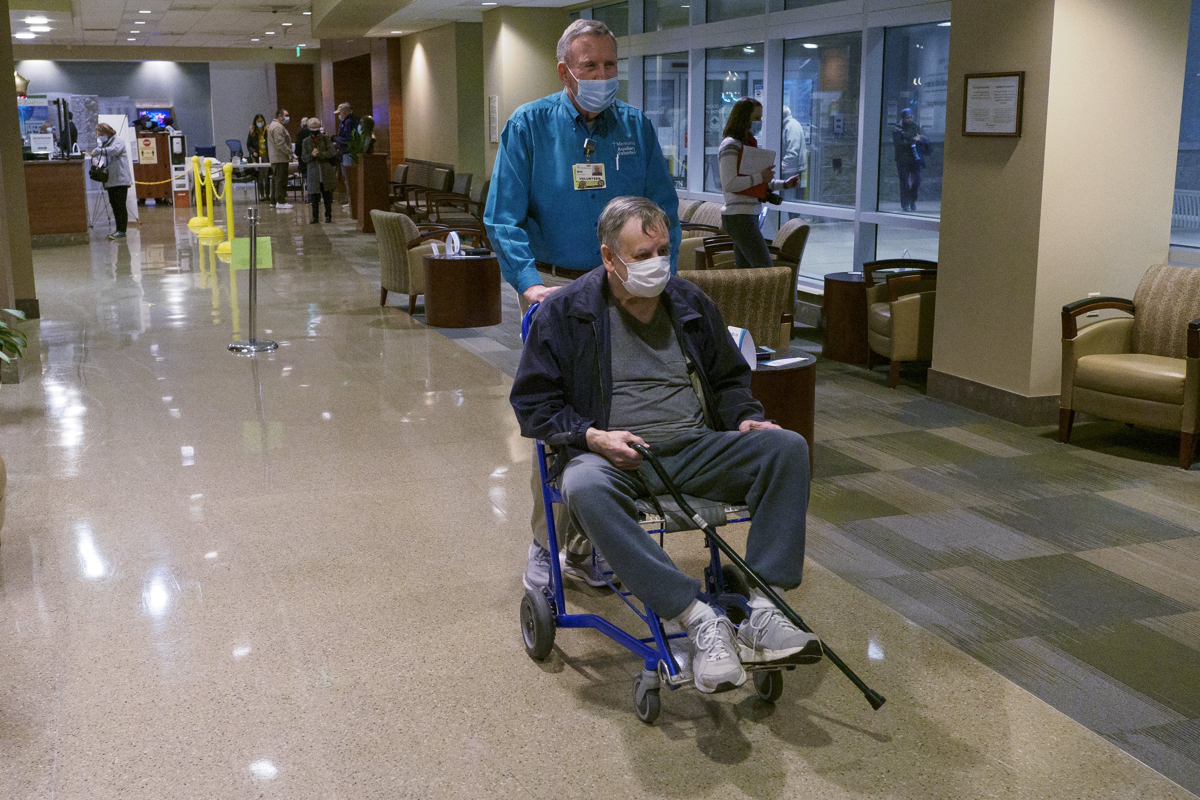 Staff photo by C.B. Schmelter / Volunteer Mike Doubleday helps Gilbert Roberts towards the shuttle at CHI Memorial Hospital on Monday, Feb. 1, 2021 in Chattanooga, Tenn. The hospital welcomed back volunteers who have been fully vaccinated.