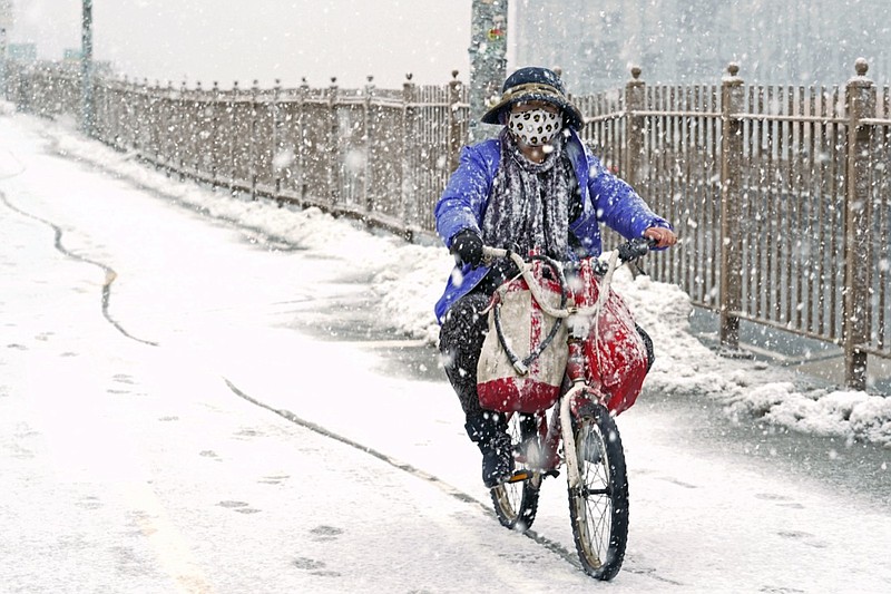 A woman rides a bicycle across the Brooklyn Bridge during a snowstorm, Sunday, Feb. 7, 2021, in the Brooklyn borough of New York. It was the second time in less than a week the area has been buffeted by heavy snowfall. (AP Photo/Kathy Willens)