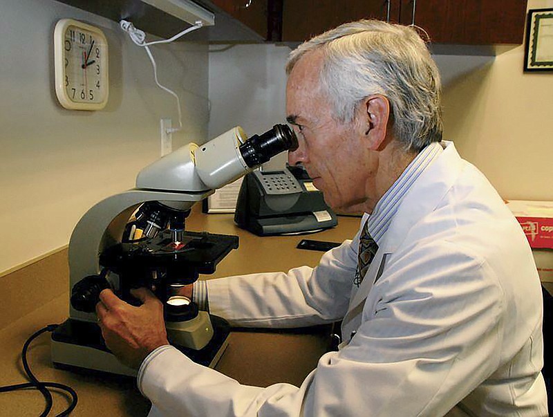 In this undated photo provided by Atlanta Allergy & Asthma, Dr. Stanley Fineman looks through a microscope at Atlanta Allergy & Asthma Center in Atlanta to examine the pollen. When Fineman started 40 years ago as an allergist in Atlanta, he told patients they should start taking their medications and prepare for the onslaught of pollen season around St. Patrick's Day. Now he tells them to start around St. Valentine's Day. (Robin B. Panethere /Atlanta Allergy & Asthma via AP)