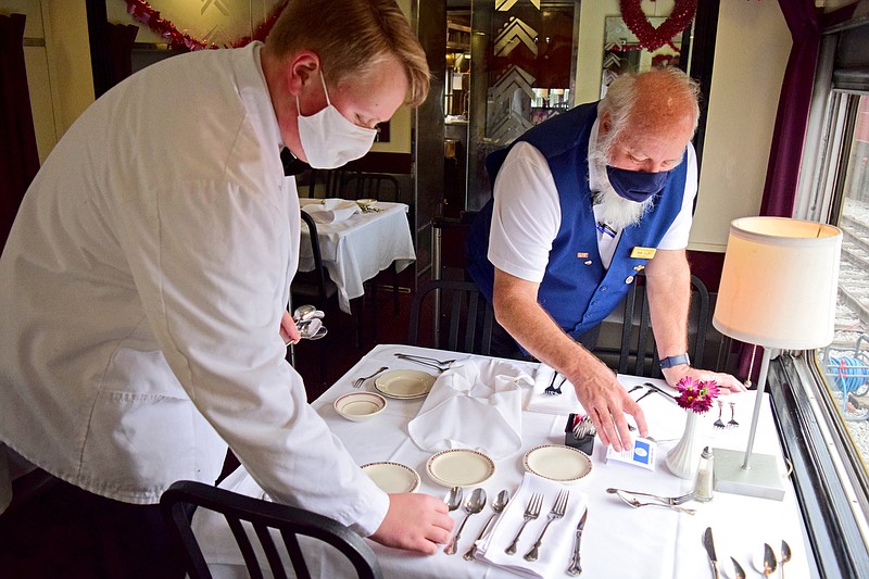 Staff Photo by Robin Rudd / From left, Dining Car Staff member Justin Freeman and Steward Bob Ralph set a table in the Traveler's Fair car.