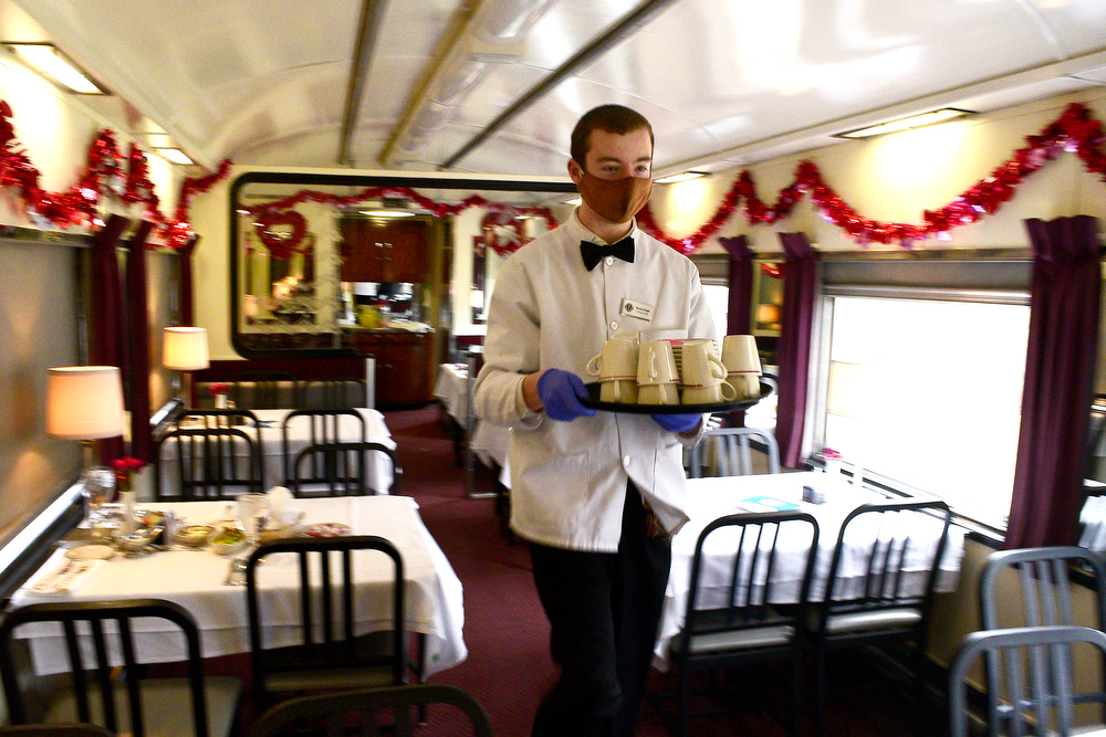 Staff Photo by Robin Rudd / Dining Car Staff member Brock Griggs caries coffee cups through one of the four dining cars.