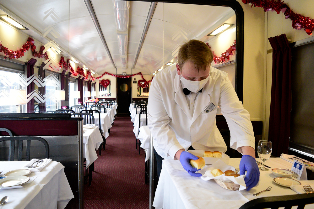 Staff Photo by Robin Rudd / Diner Car Staff member Justin Freeman places rolls on a table.