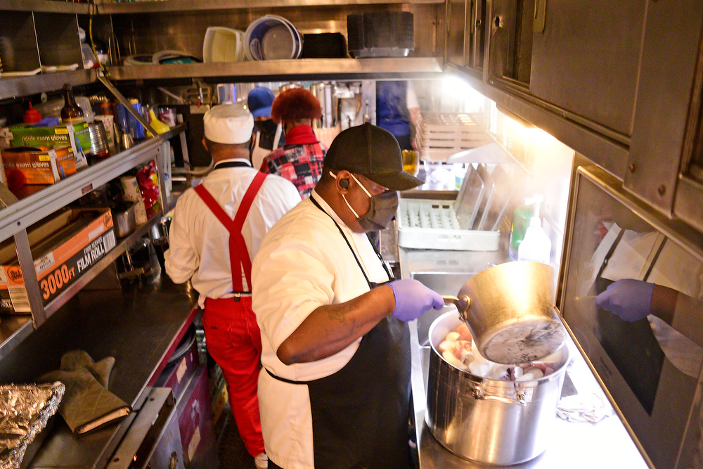 Staff Photo by Robin Rudd / The kitchen car is a tight work environment. In the Foreground chef Terrence Smith prepares mash potatoes.