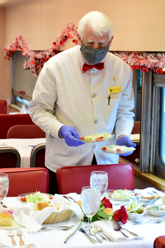Staff Photo by Robin Rudd / Dining Car Staff member Jim Jordan places salads on a table in the car, Silver Lake.