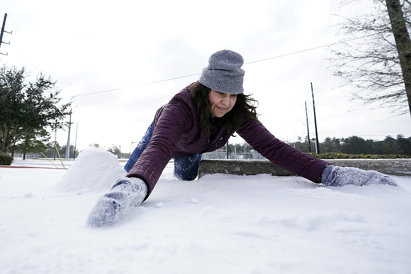 Cristina Lucero gathers snow while trying to build a snowman Monday, Feb. 15, 2021, in Houston. A winter storm dropping snow and ice sent temperatures plunging across the southern Plains, prompting a power emergency in Texas a day after conditions canceled flights and impacted traffic across large swaths of the U.S. (AP Photo/David J. Phillip)