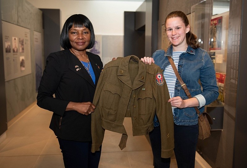 U.S. Air Force photo by Airman 1st Class Jennifer Zima / Col. Edna Cummings (Retired), producer of "The Six Triple Eight," and Sophie Green, a guest at film's screening at the Cambridge American Cemetery in England, hold a 6888th Central Postal Directory Battalion uniform belonging Pvt. Grace Vairin. The jacket is on loan to the 6th Cavalry Museum for its new exhibit on the battalion.